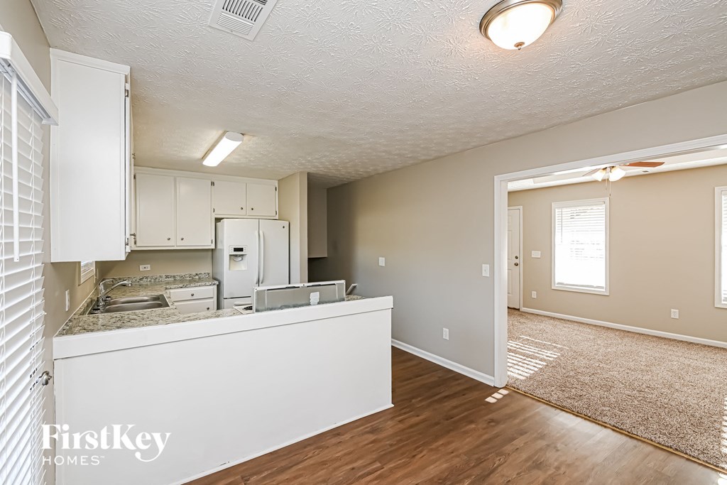 A kitchen area with a refrigerator, cabinets, and a countertop.
