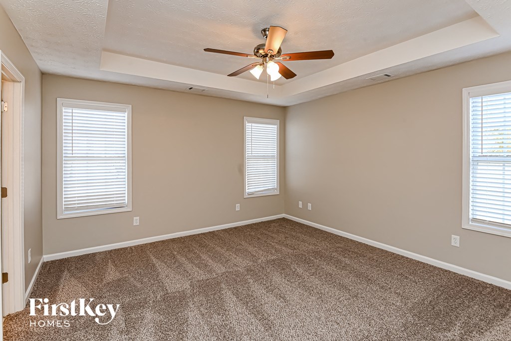 A room with a ceiling fan and two windows.