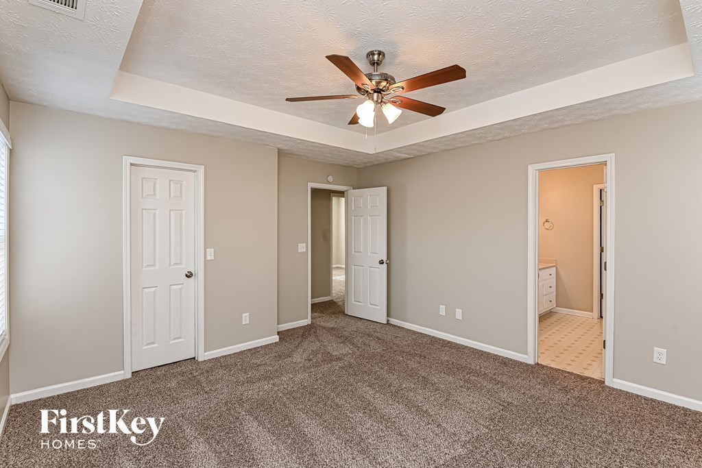 A spacious room with a ceiling fan and carpeted floor.