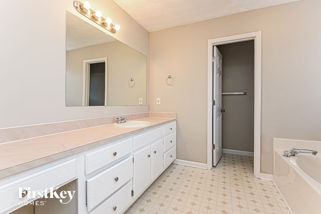 A bathroom with a white vanity and a large mirror.