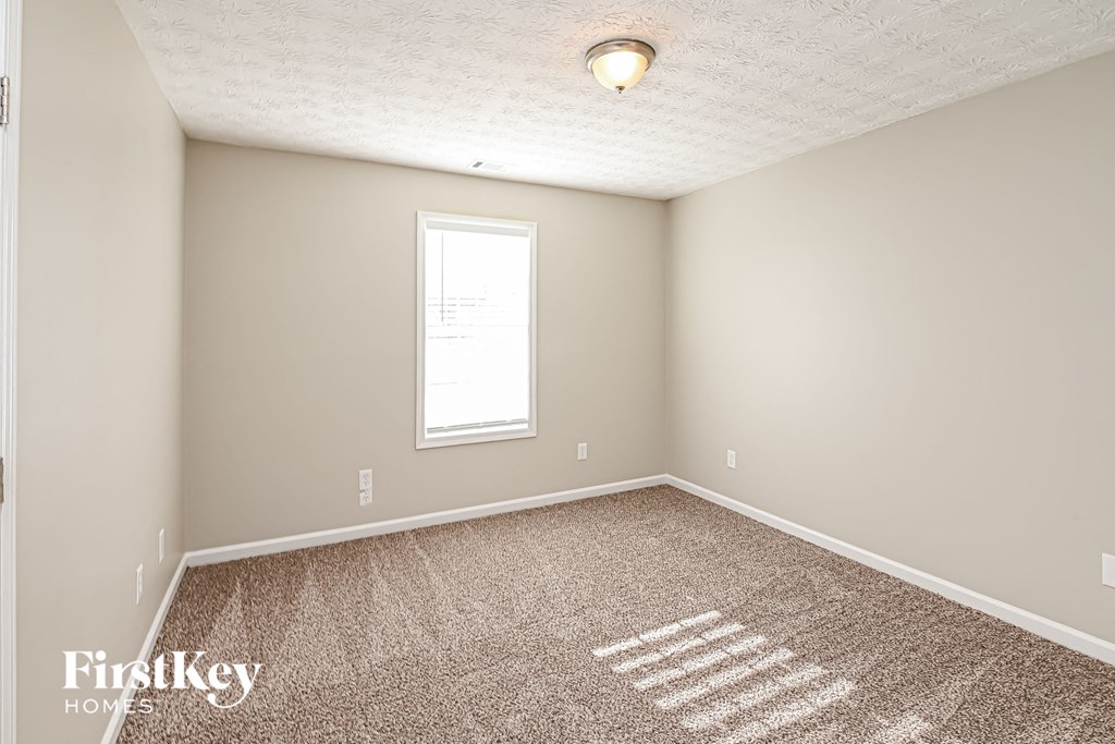 A room with a carpeted floor and a window.
