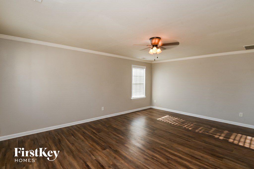 the living room with wood flooring and a ceiling fan