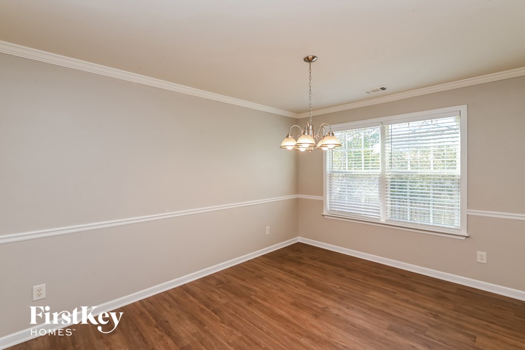an empty dining room with wood floors and a window