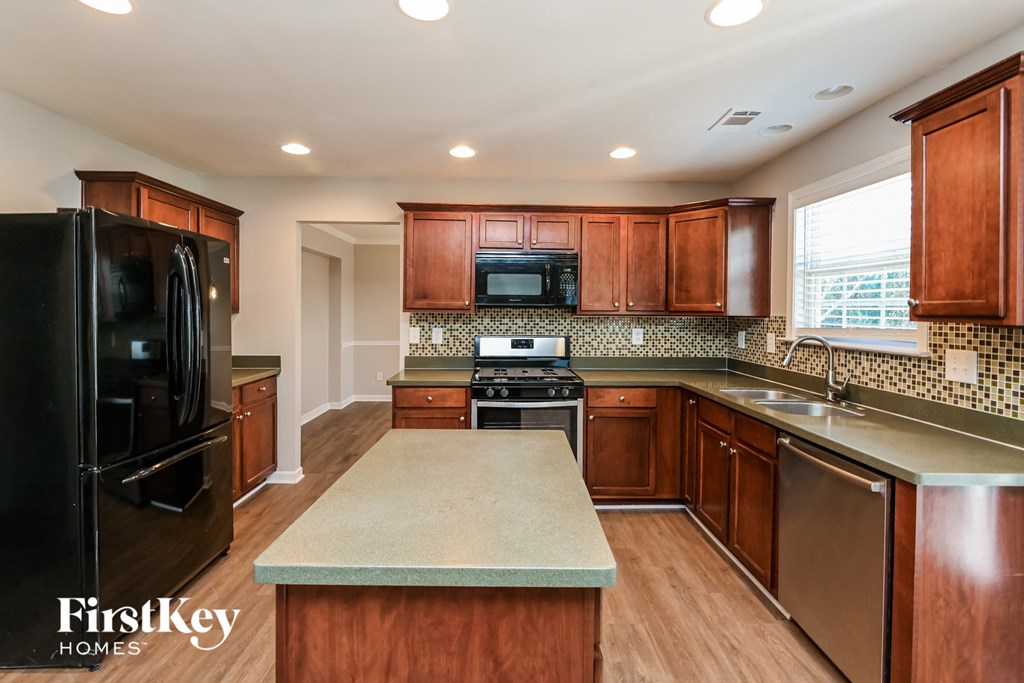 an updated kitchen with black appliances and wood cabinets