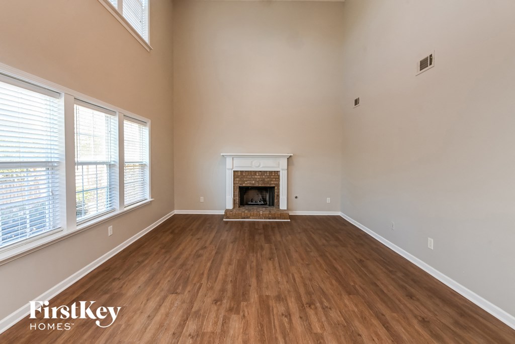 an empty living room with a fireplace and wood flooring