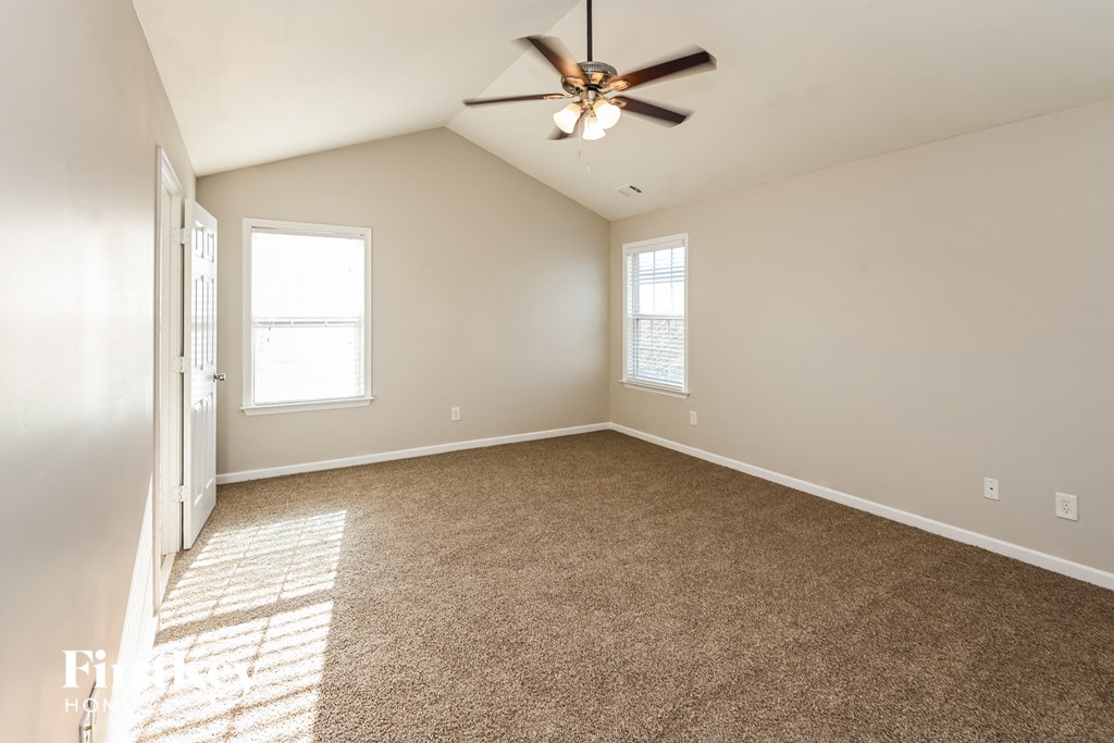 an empty living room with carpet and a ceiling fan