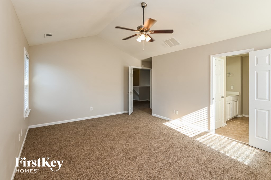 a spacious living room with carpet and a ceiling fan