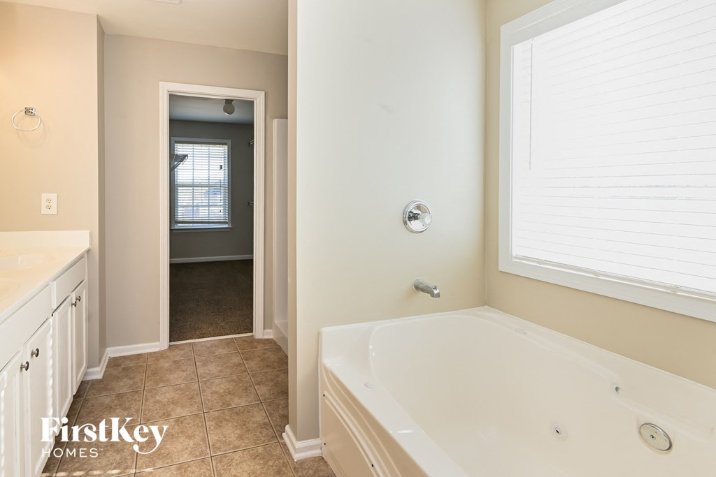 a bathroom with a large white tub and a sink and a window