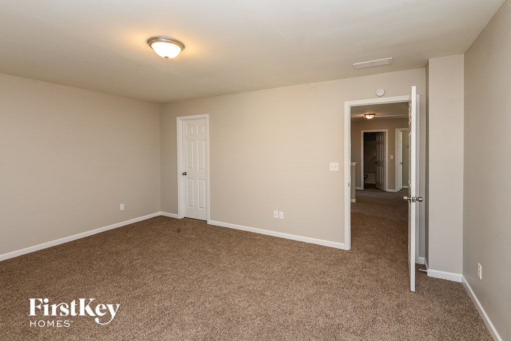 a bedroom with a carpeted floor and a door to a hallway