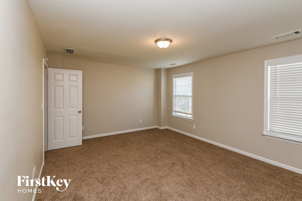 a bedroom with beige carpet and a white door and window