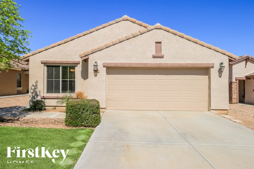 A house with a garage door and a tree in front of it.