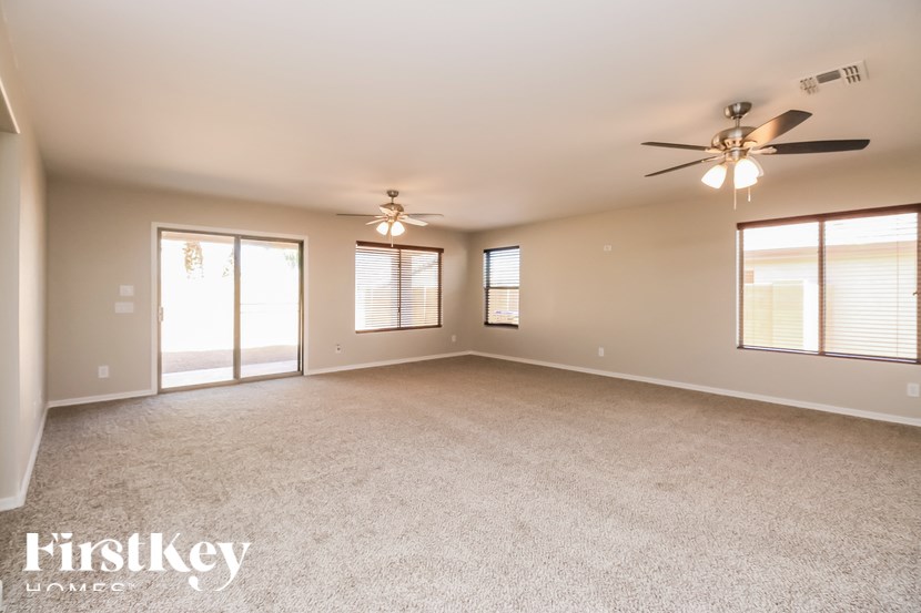 A spacious room with a ceiling fan and carpeted floor.