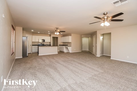 A spacious living room with a kitchen in the background.