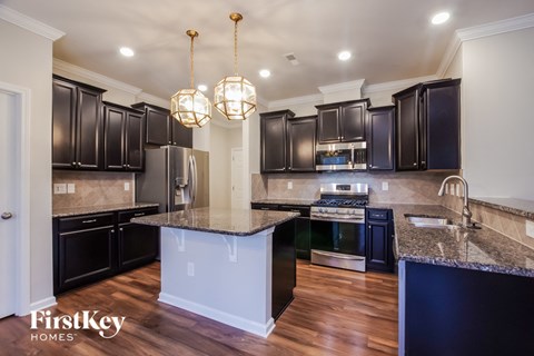 A kitchen with dark cabinets and a marble island.
