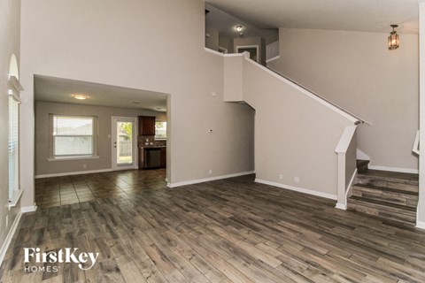 A spacious living room with wood flooring and a staircase leading to the upper level.