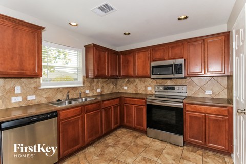A kitchen with brown cabinets and a FirstKey Homes dishwasher.