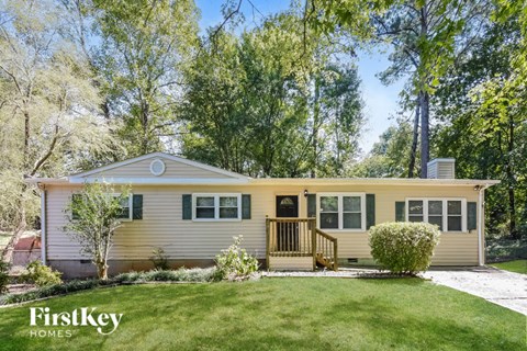 A house with a porch and a tree in front of it.