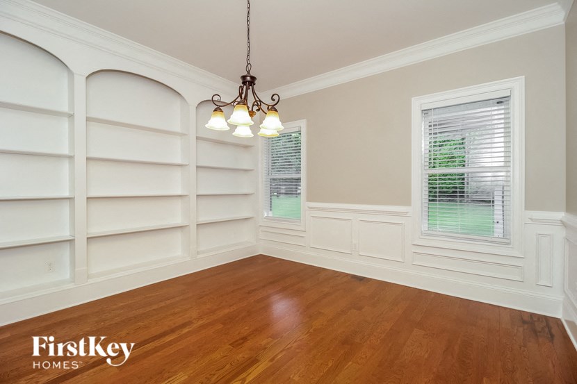 an empty dining room with white shelves and a window