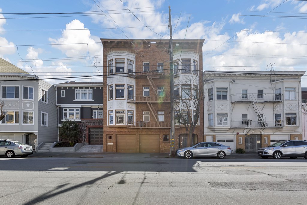 A street view of a residential area with cars parked on the side of the road.