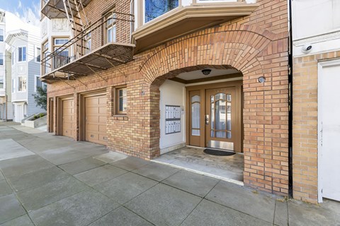 A brick building with a balcony and a white door.