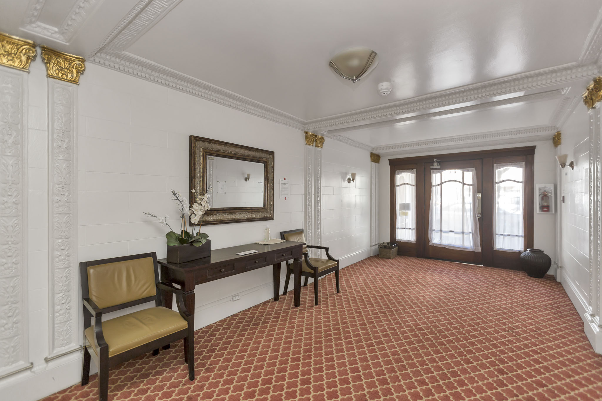 A room with a red tiled floor and a white wall with a mirror and a chair.