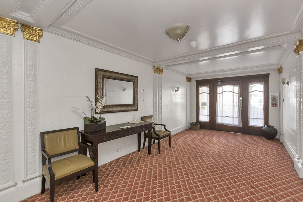 A room with a red tiled floor and a white wall with a mirror and a chair.