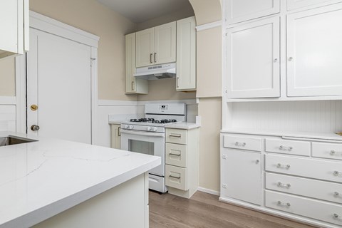 A kitchen with white cabinets and a white countertop.