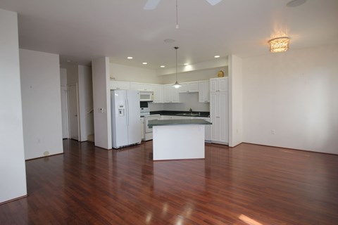 A kitchen with white cabinets and a wooden floor.