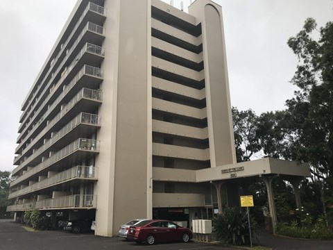 A tall building with a parking lot in front of it.