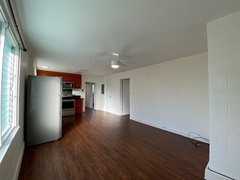 A kitchen with a refrigerator and wooden floors.