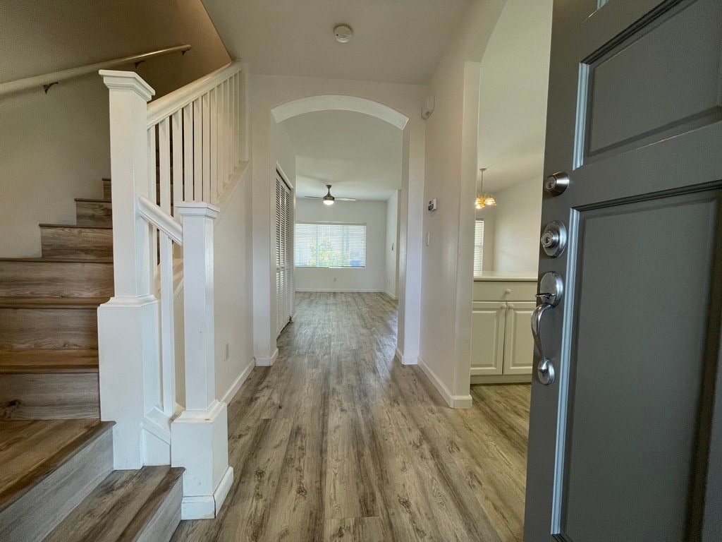 A hallway with a staircase on the left and a door on the right.