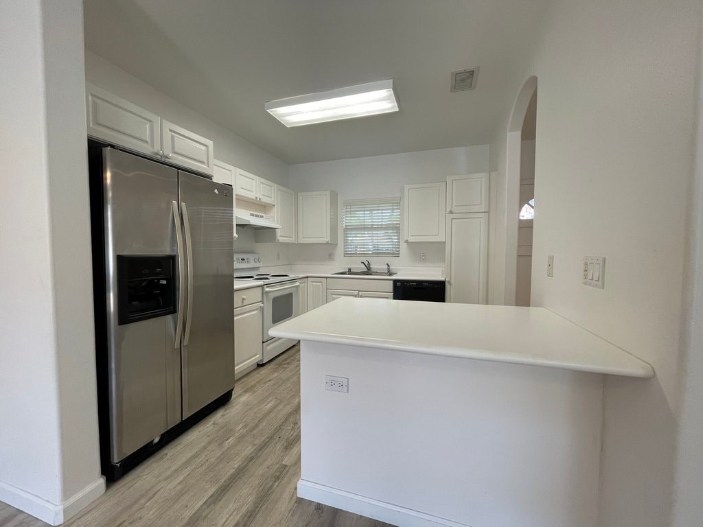 A kitchen with white cabinets and a stainless steel refrigerator.