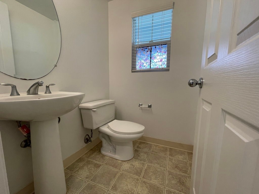 A bathroom with a toilet, sink, and a window with stained glass.
