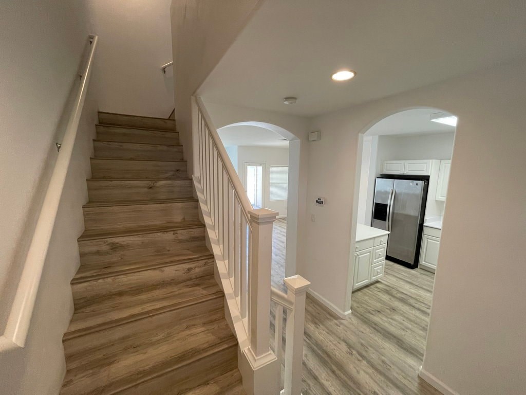 A staircase with wooden steps and white railings leads to a kitchen area.