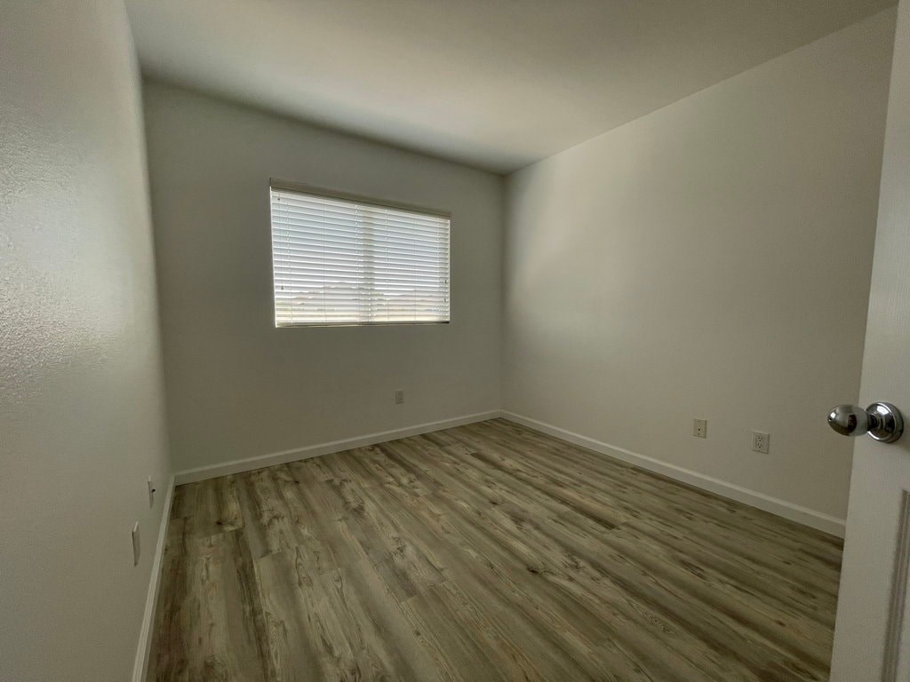 A room with wooden flooring and a window with blinds.