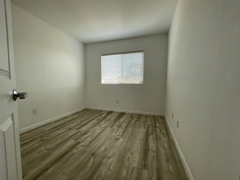 A room with wooden flooring and a window with blinds.