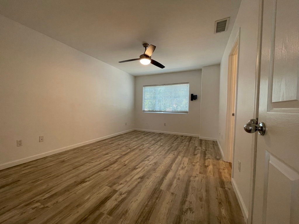 A room with wooden flooring and a ceiling fan.