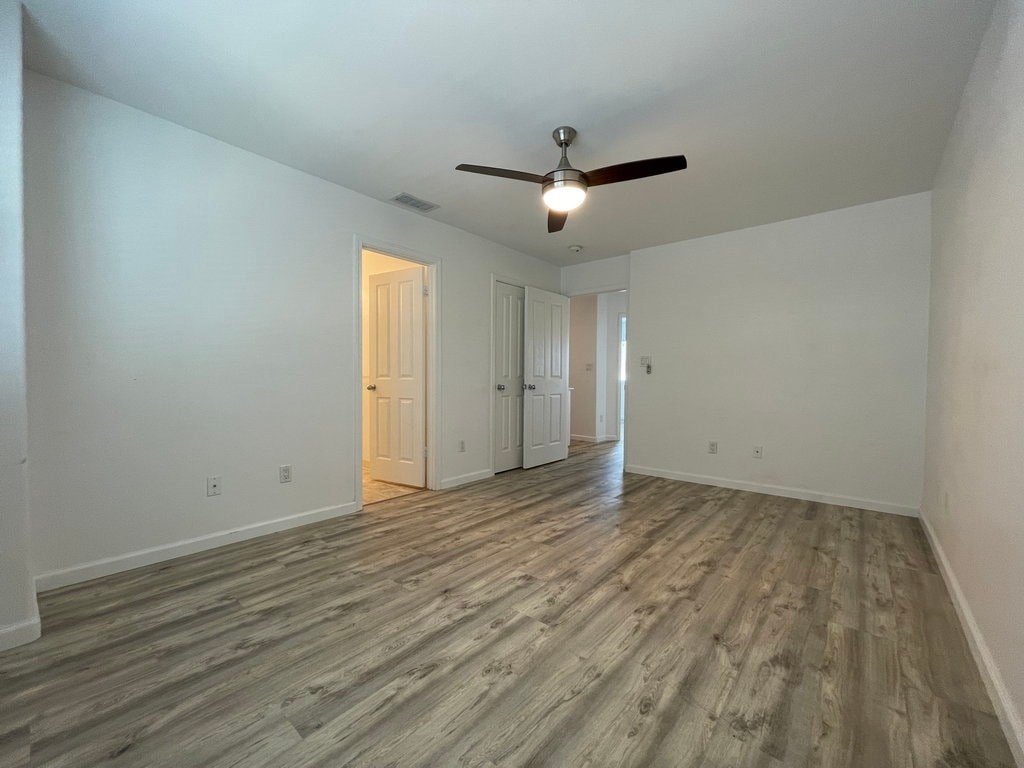 A room with a ceiling fan and wooden flooring.