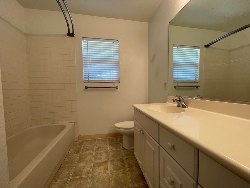 A bathroom with a white tub, sink, and toilet.