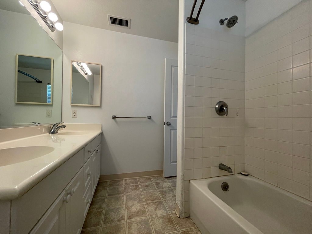 A white bathroom with a sink, mirror, and bathtub.