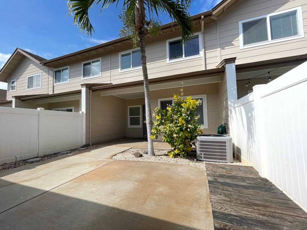 A house with a white fence and a palm tree in front.