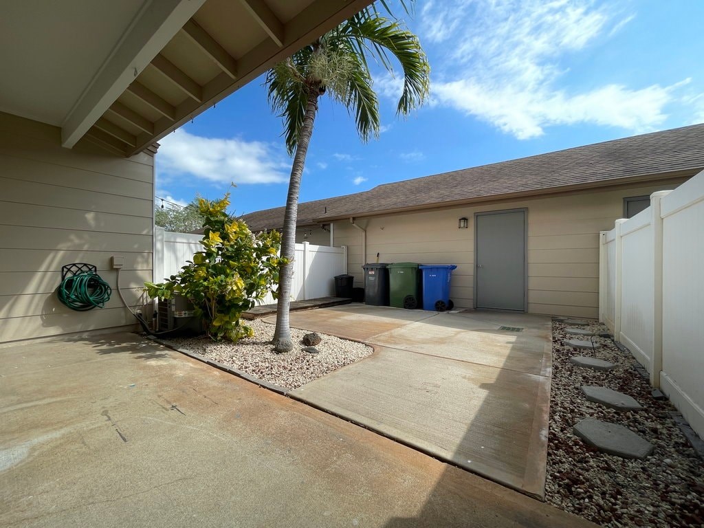 A palm tree stands in a driveway next to a house.