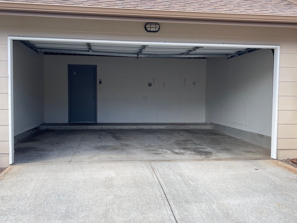 A garage with a closed door and a wall on the left side.