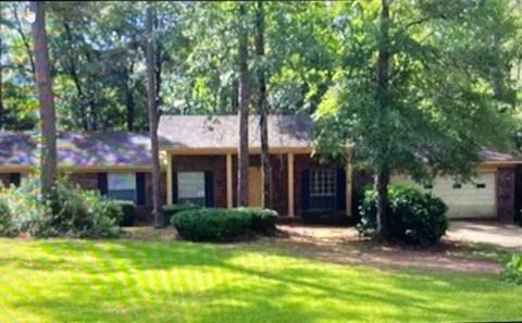 A house with a green lawn and trees in front.