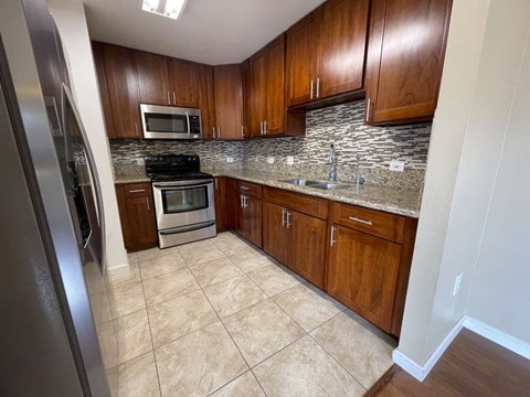 A kitchen with wooden cabinets and a tile backsplash.