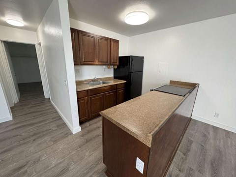 A kitchen with a black refrigerator and brown cabinets.