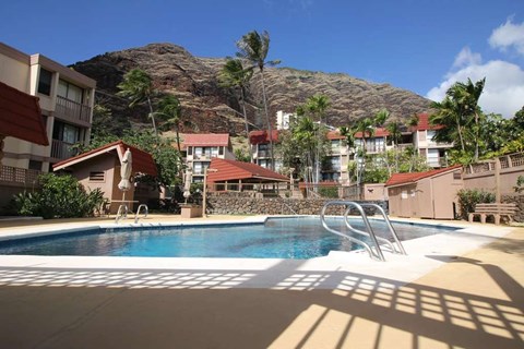 A pool in front of a mountain with a building in the background.
