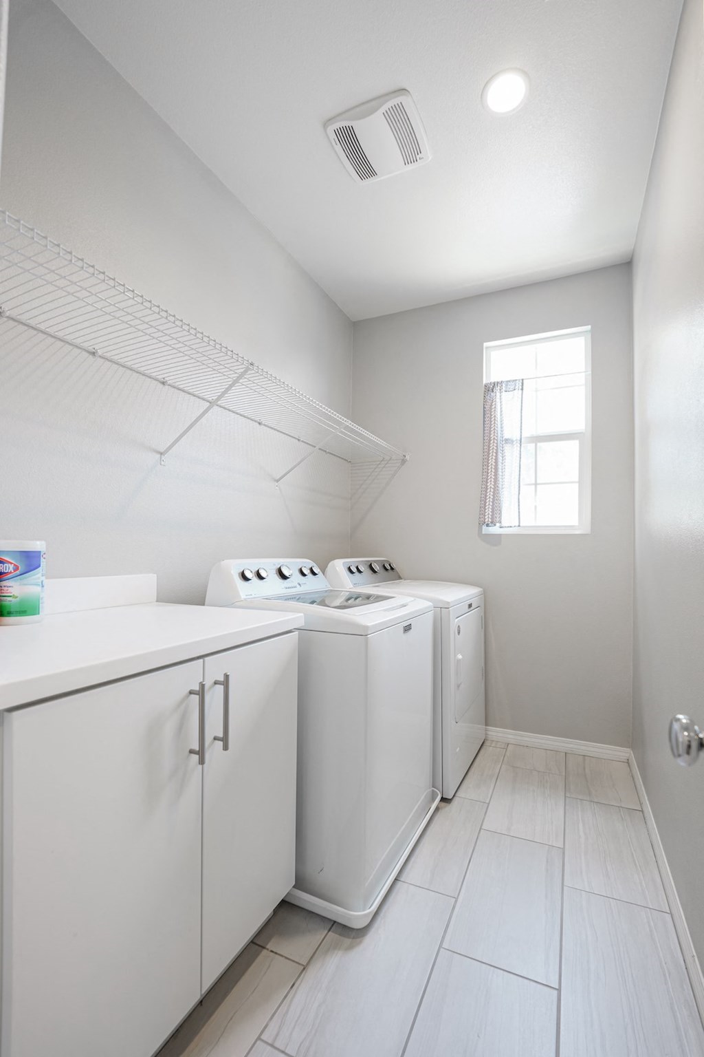 an empty laundry room with white appliances and a window