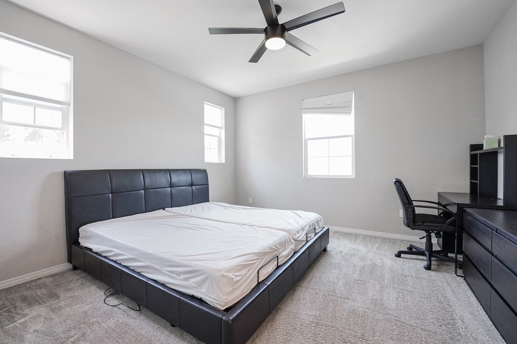 an empty bedroom with a bed and a ceiling fan