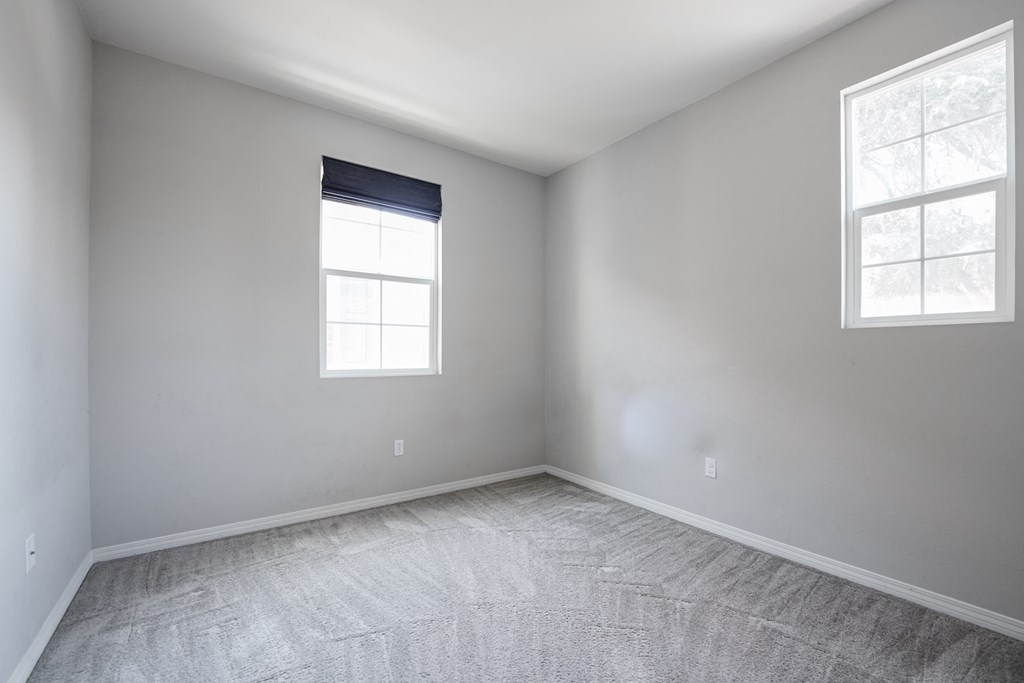 an empty room with two windows and white walls